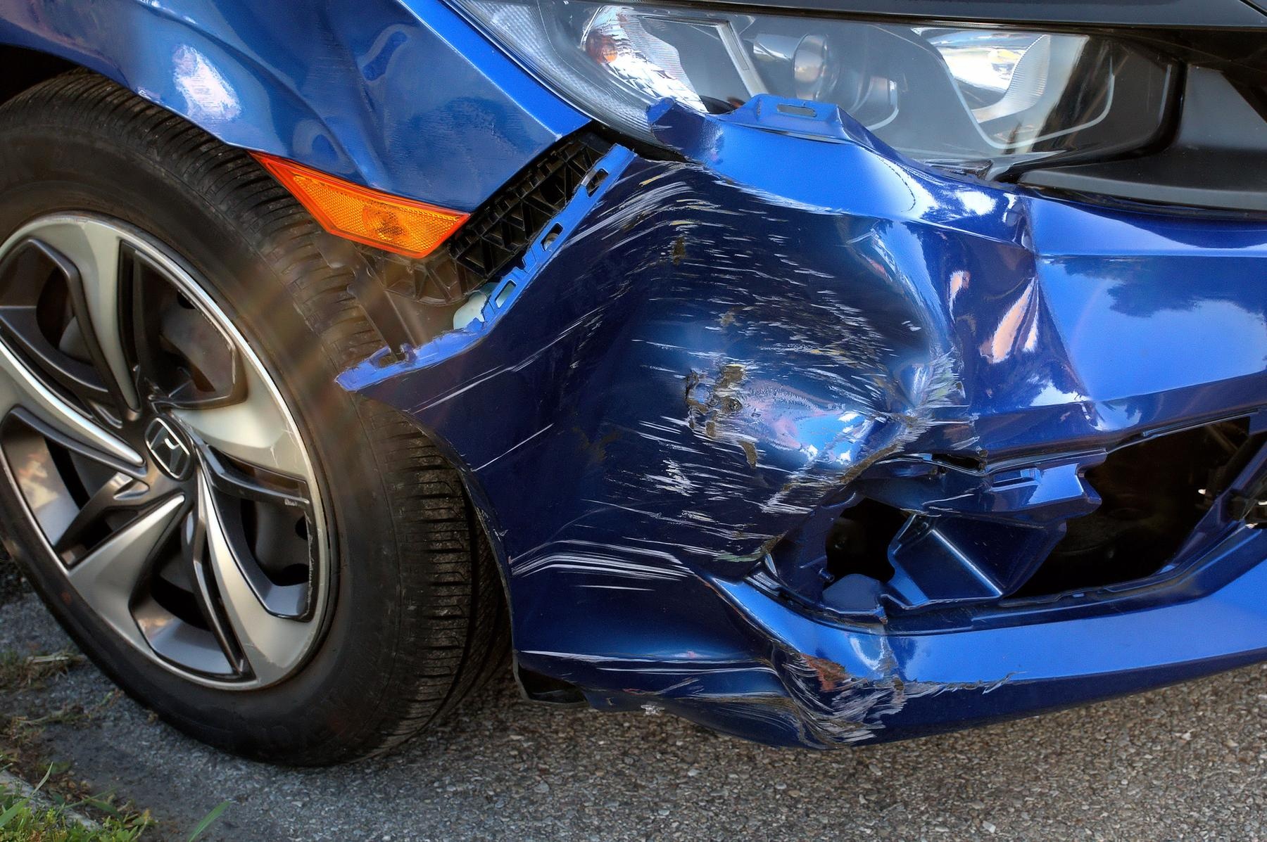 Blue car with front-end damage, showing scratches and dents, representing collision repair needs for Lake Area Collision services.