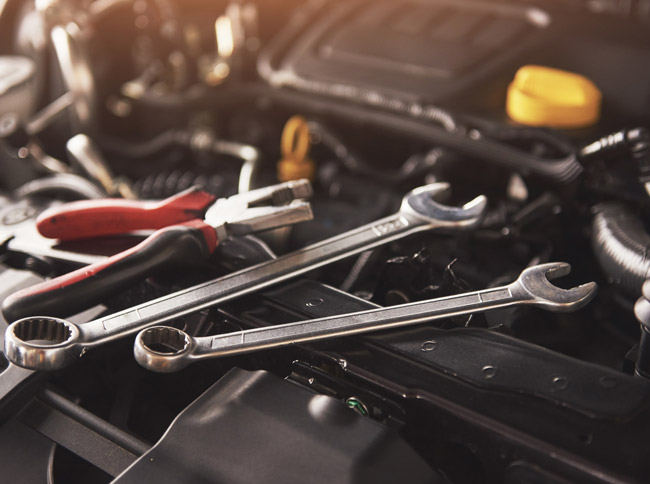 Tools including wrenches and pliers on an auto engine, representing Lake Area Collision's commitment to quality auto repair services.